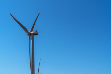 the towering elegance of a wind turbine set against a clear blue sky, symbolizing modern renewable energy and technological advancement in harnessing the power of the wind