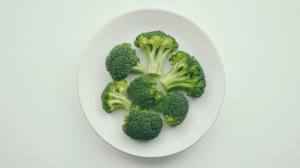 Fresh broccoli florets on white plate: minimalist green cuisine