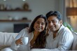 © Dilshad - Smiling Indian Couple Sipping Coffee and Laughing Together on Sofa