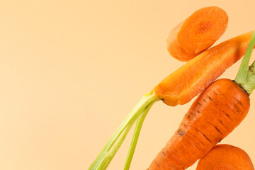 Canvas Print - Whole and cut fresh carrots on pale orange background, closeup. Space for text