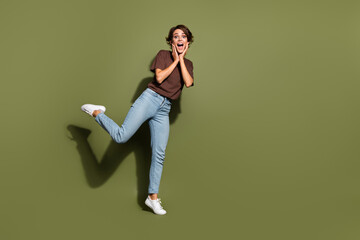 Wall Mural - Full length photo of overjoyed astonished girl wear oversize t-shirt denim pants palms on cheek staring isolated on green color background