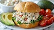 © Lucy - Fresh and Healthy Chicken Salad Sandwich on a Rustic Bread Roll with Avocado, Tomatoes, and Lettuce - Perfect for a Light Lunch or Snack. Delicious and Nutritious Meal Idea.