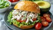 © Lucy - Fresh and Healthy Chicken Salad Sandwich on a Rustic Bread Roll with Avocado, Tomatoes, and Lettuce - Perfect for a Light Lunch or Snack. Delicious and Nutritious Meal Idea.