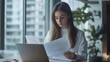 © Irina Ukrainets - A young woman in a cozy workspace examines important documents. She sits calmly at her desk, studying the papers thoughtfully. The natural light creates a serene atmosphere. AI