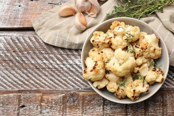 Canvas Print - Baked cauliflower in bowl, garlic and thyme on wooden table, flat lay. Space for text