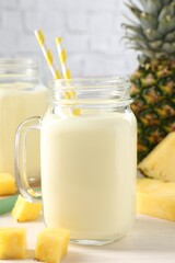 Poster - Tasty pineapple smoothie in mason jar and fresh fruit on white wooden table