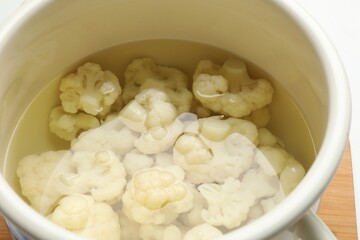 Cauliflower in pot with water on table, closeup