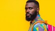 © Nataliia_Trushchenko - A man with a beard and a colorful shirt is standing in front of a yellow background. He is wearing a backpack and has a serious expression on his face