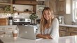 © Attasit - Smiling businesswoman using a laptop at a kitchen island, enjoying a coffee break