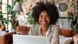 © Attasit - Businesswoman smiling while using a laptop, feeling productive at home