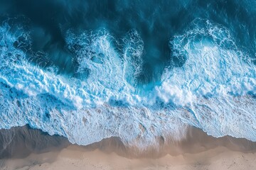 Top-down aerial view of ocean waves crashing on a beach, presenting a mesmerizing pattern of blue water and white foam, perfect for background or nature-themed projects.