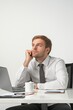 © Andrii Zastrozhnov - A man in a white shirt and gray tie sits at a desk with a laptop and a cup. He is deep in thought, possibly contemplating a work-related issue
