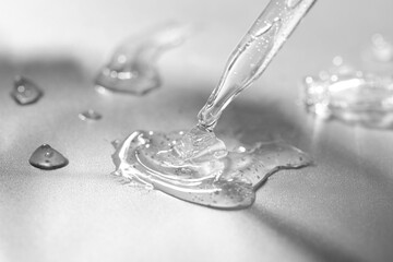 Poster - Dripping cosmetic serum from pipette on grey background, closeup