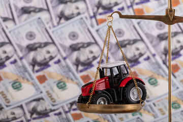 Wall Mural - A tractor sits on a gold scale against the backdrop of $100 bills.