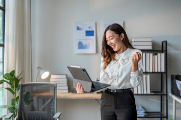 Wall Mural - happy businesswoman celebrating success while holding tablet in office