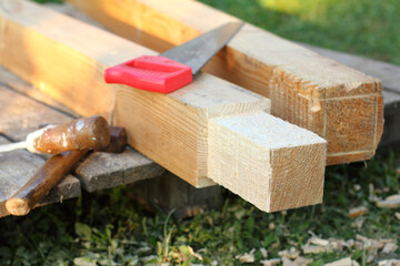 wooden blanks and carpentry tools on the grass in the garden. making supports for a gazebo