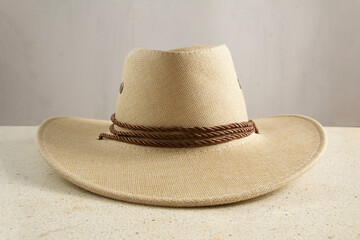 closeup of brown straw hat and hat strap detail front view, gray background on table