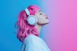 © Saulo Collado - Woman with pink hair wearing white headphones, listening to music against a solid-colored background.