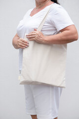 Wall Mural - Close up of woman holding eco or reusable shopping bag against white wall background