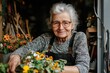 © Milos - An elderly floral artisan, wearing glasses and an apron, is crafting intricate flower decorations at her indoor workspace, demonstrating her lifelong dedication and joy.