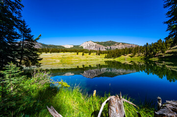 Yellowstone National Park's Trout Lake with beautiful reflections in the water and sun burst in the sky with mountains in the background