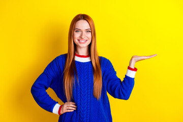 Wall Mural - Photo portrait of pretty young girl hold empty space wear trendy blue knitwear outfit isolated on yellow color background