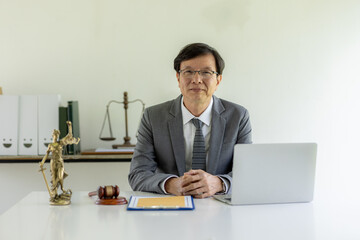 Portrait of mature asian notary public or lawyer working in the office,Male lawyer working at documents laptop in office.