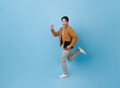 © NaMong Productions - Full length Asian man holding tablet running with happy smile isolated on blue background. Happy man joyful run in copy space.