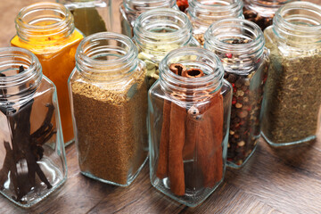 Wall Mural - Different spices in glass jars on wooden table