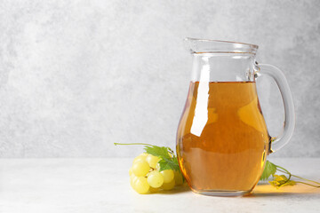 Wall Mural - Tasty grape juice in jar and berries on light table. Space for text