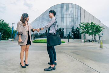 Two business man and woman shake hands outside a modern office building and successful business dealings. professionalism in a corporate setting. reflecting of collaboration and strategic planning.