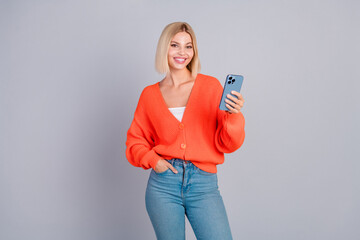 Wall Mural - Photo of pretty young girl hold smart phone orange cardigan isolated on grey color background