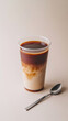 © Stewart Bruce - A cinematic medium shot of a tall, slim, transparent plastic coffee cup filled with coffee,  studio light; isolated on a beige background. perfect for focused advertising