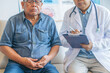 © MD Media - A doctor is examining an elderly man with stomach pain in the medical room, holding his belly. Portrait of senior man sharing health issues struggles with his medical professional carer practitioner