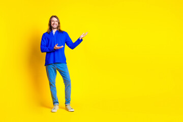 Photo of glad positive handsome nice man wear trendy blue clothes recommend empty space isolated on yellow color background