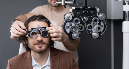 Ophthalmologist office, doctor use trial frame for checks vision of young italy man in modern clinic for optical glasses