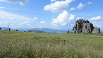 Poster - A large rock formation stands tall in the distance, with a grassy field and blue sky overhead.