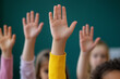 © SnapVault - A classroom scene featuring several children's hands raised in unison, indicating participation or answering a question in classroom. The faces are softly blurred in the background