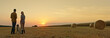© StockMediaSeller - Two farmers admire the sunset over a field with a Golden Retriever by their side,wide shot