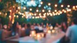 © Kenny - Blurred outdoor party with string lights and candlelit tables in a garden setting