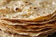 © Irina B - Stack of thin flatbreads with golden brown spots, closely arranged in a pile, highlighting their texture and crispiness.