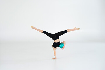 rhythmic gymnast performing with ball, showing skills and stay isolated on white background. Concept of sport, active lifestyle, hobby.