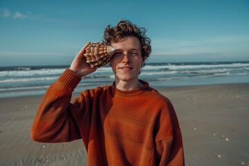 Poster - Man holding a seashell to his ear on the beach. AI.