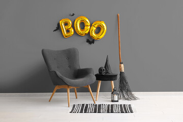 Poster - Armchair, broom and text BOO made of balloons hanging on orange wall in living room