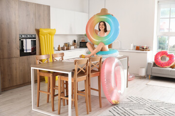 Poster - Young woman with swim rings ready for summer vacation in kitchen