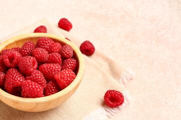 wooden bowl with fresh raspberries on light background