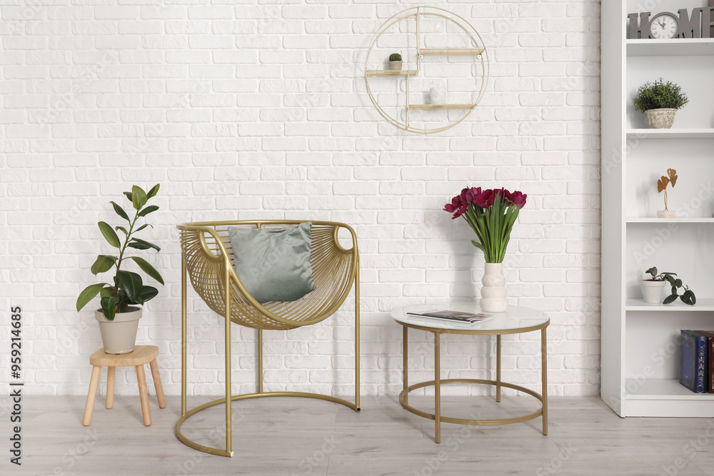 Comfortable chair with pillow, coffee table and flowers near white wall