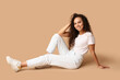 © Pixel-Shot - Happy young African-American woman sitting on beige background
