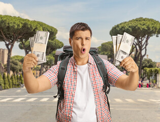 Happy male tourist with a backpack holding money in Rome