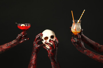 Wall Mural - Many hands of zombies with glasses of cocktails and skull on black background. Halloween celebration